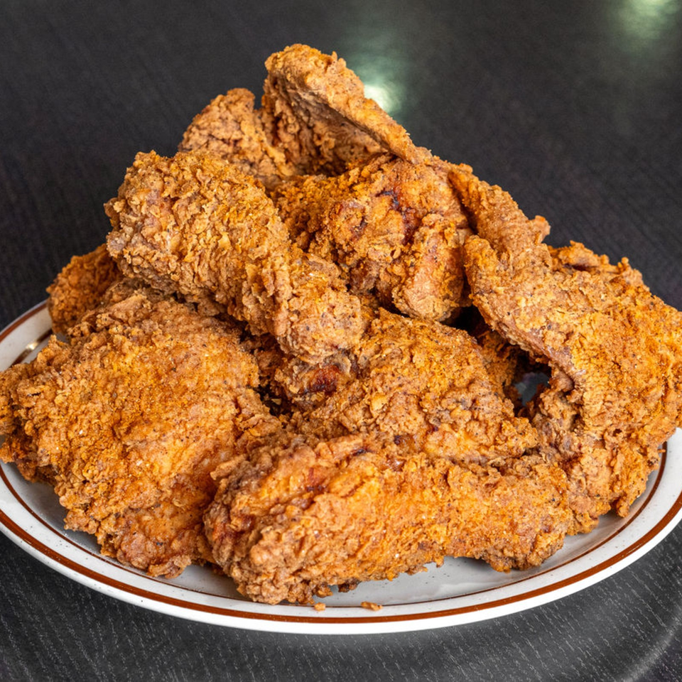Plate piled high with crispy golden-brown fried chicken pieces on a dark tabletop.