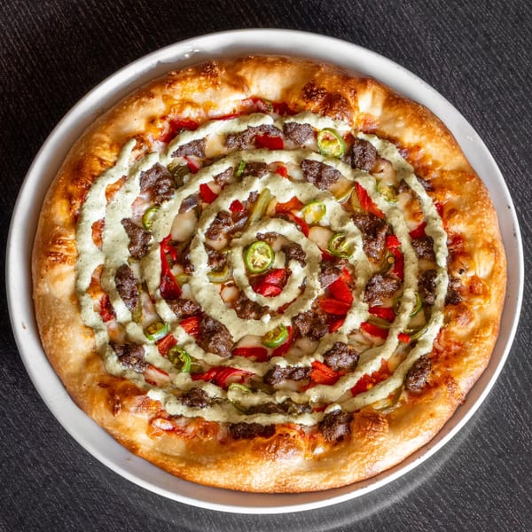 Mirchi Cafe's Masala Pizza, topped with ground meat, red peppers, jalapenos, and a spiral of green sauce.
